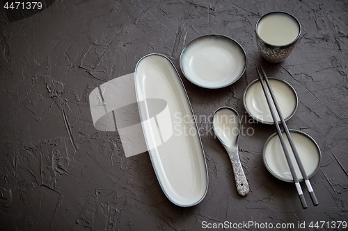 Image of Set of empty ceramic dishes for sushi and rolls on a black stone table