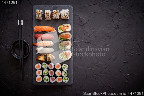 Image of Sushi rolls set with salmon and tuna fish served on black stone board