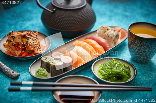 Image of Asian food assortment. Various sushi rolls placed on ceramic plates