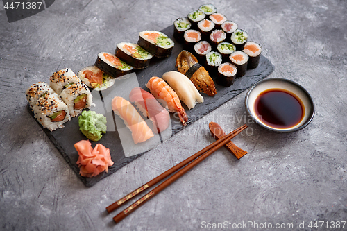 Image of Composition of different kinds of sushi rolls placed on black stone board