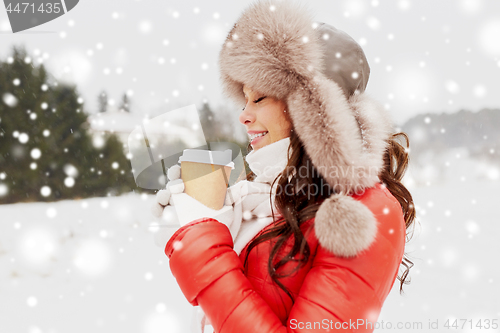 Image of happy woman in winter fur hat with coffee outdoors