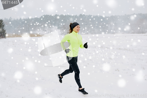 Image of happy woman running along snow covered winter road