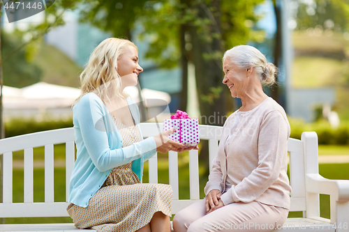 Image of daughter giving present to senior mother at park