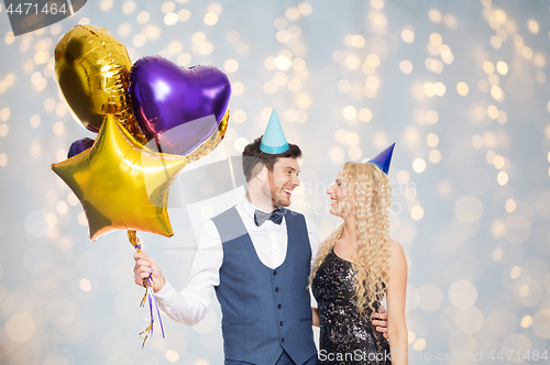 Image of happy couple in party hats with balloons