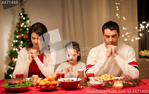 Image of family praying before meal at christmas dinner