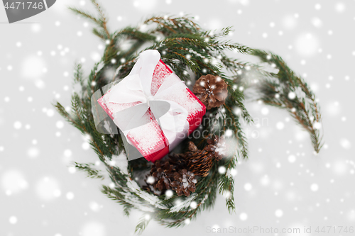 Image of christmas gift and fir wreath with cones on snow