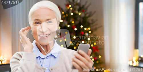 Image of senior woman with earphones and phone on christmas