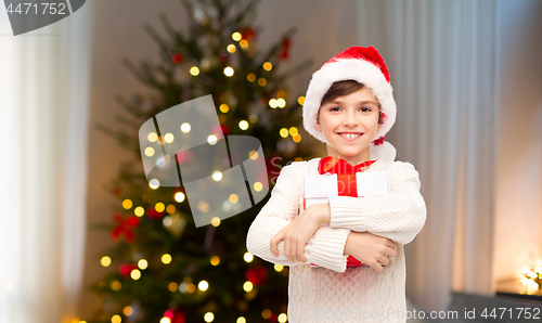 Image of happy boy in santa hat with gift box on christmas