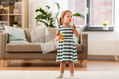 Image of little girl blowing soap bubbles at home
