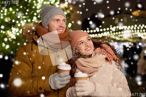 Image of happy young couple with coffee at christmas market