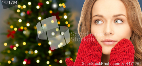 Image of close up of woman in mittens over christmas tree