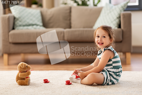 Image of little girl playing with toy tea set at home