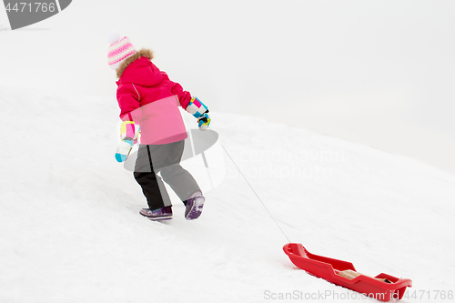 Image of little girl with sled on snow hill in winter