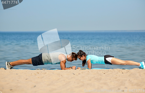 Image of couple doing plank exercise on summer beach