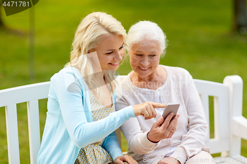 Image of daughter and senior mother with smartphone at park