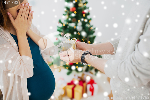 Image of husband giving christmas present to pregnant wife