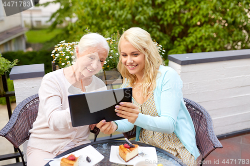 Image of daughter with tablet pc and senior mother at cafe