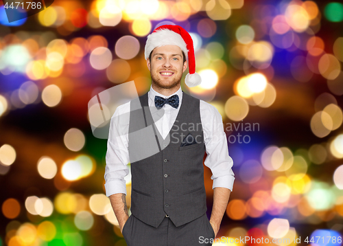 Image of happy man in santa hat and suit at christmas