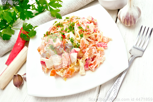 Image of Salad of surimi and tomatoes with mayonnaise on wooden table
