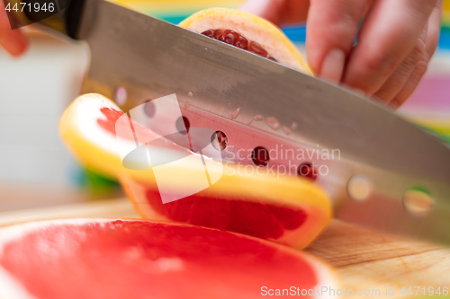 Image of Women\'s hands Housewives cut with a knife fresh grapefruit on th