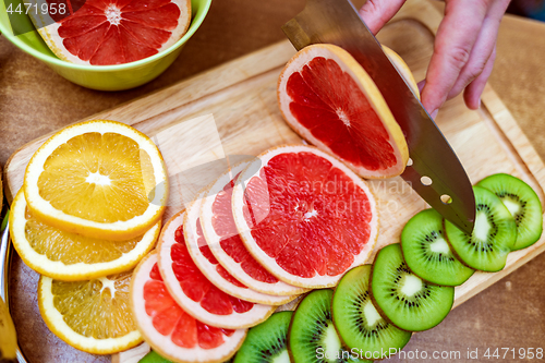 Image of Women\'s hands Housewives cut with a knife fresh grapefruit on th