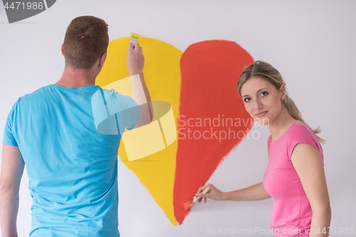 Image of couple are painting a heart on the wall