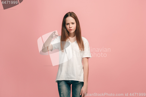 Image of The teen girl pointing to you, half length closeup portrait on pink background.