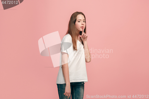 Image of The young teen girl whispering a secret behind her hand over pink background