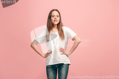 Image of The happy teen girl standing and smiling against pink background.