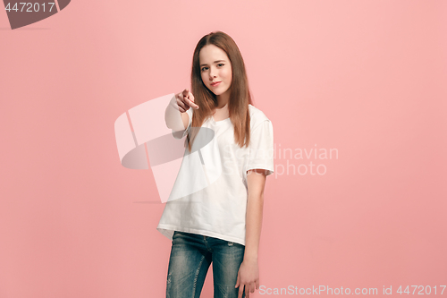 Image of The happy teen girl pointing to you, half length closeup portrait on pink background.