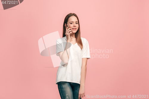 Image of The happy teen girl standing and smiling against pink background.