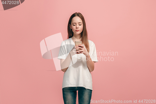 Image of The happy teen girl standing and smiling against pink background.