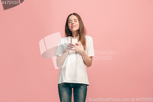 Image of The happy teen girl standing and smiling against pink background.