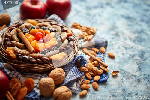 Image of Composition of dried fruits and nuts in small wicker bowl placed on stone table