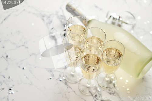 Image of Champagne glasses and bottle placed on white marble background