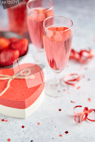 Image of Bottle of rose champagne, glasses with fresh strawberries and heart shaped gift