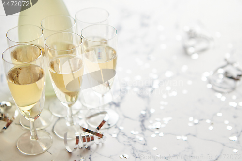 Image of Champagne glasses and bottle placed on white marble background