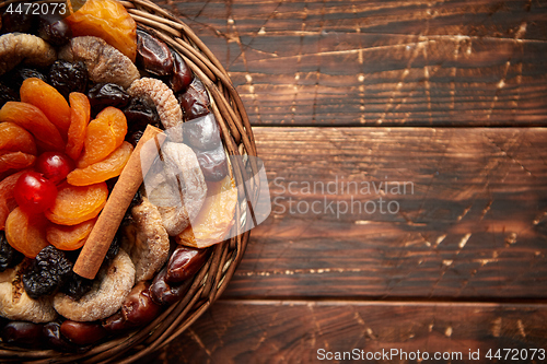 Image of Mix of dried fruits in a small wicker basket on wooden table