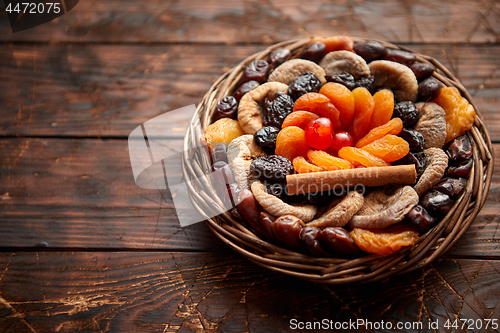 Image of Mix of dried fruits in a small wicker basket on wooden table