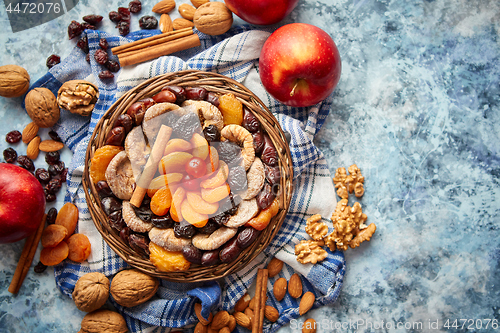 Image of Composition of dried fruits and nuts in small wicker bowl placed on stone table