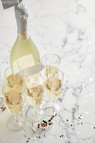 Image of Champagne glasses and bottle placed on white marble background