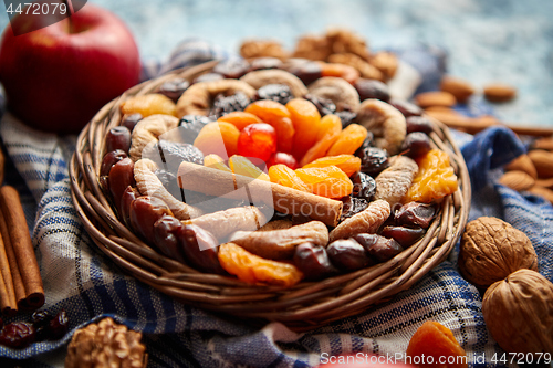 Image of Composition of dried fruits and nuts in small wicker bowl placed on stone table