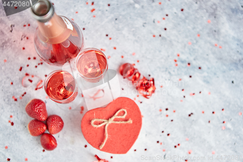 Image of Bottle of rose champagne, glasses with fresh strawberries and heart shaped gift