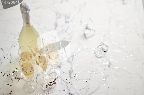 Image of Champagne glasses and bottle placed on white marble background