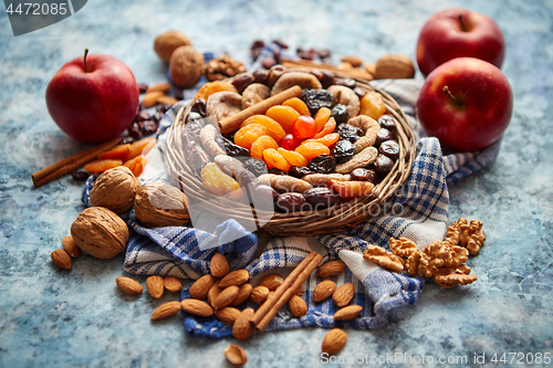 Image of Composition of dried fruits and nuts in small wicker bowl placed on stone table