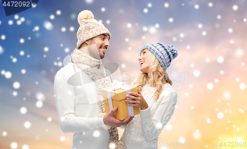 Image of smiling couple in winter clothes with gift box