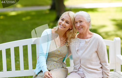 Image of daughter with senior mother hugging on park bench