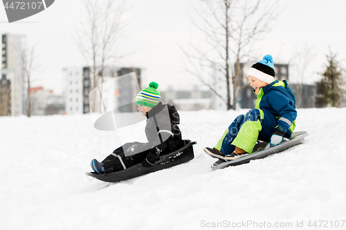 Image of kids sliding on sleds down snow hill in winter