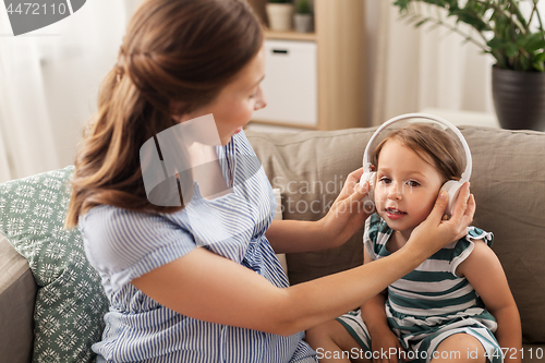 Image of pregnant mother and little daughter in headphones