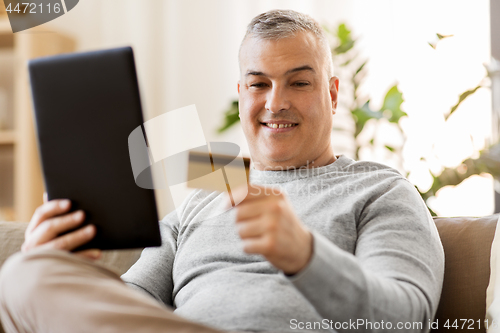 Image of man with tablet pc and credit card on sofa at home